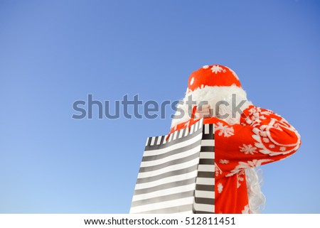 Merry Christmas with joyful Santa Claus ready to ship and delivering gift packages on sunny blue sky outdoors background. Happy time for amazement and excitement