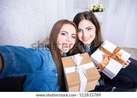 two happy beautiful women taking selfie photo with presents in living room