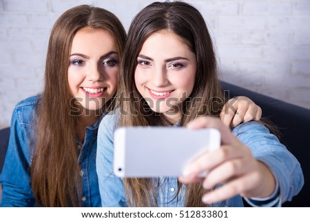 two young attractive women taking selfie photo with smart phone
