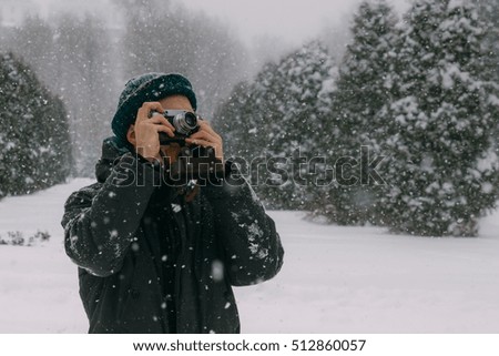 man shooting on old camera snowflakes in the park winter 