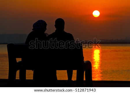 Couple watching sunset sitting on a bench