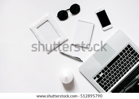 White office desk with laptop, smartphone and notebook . Top view with copy space, flat lay.