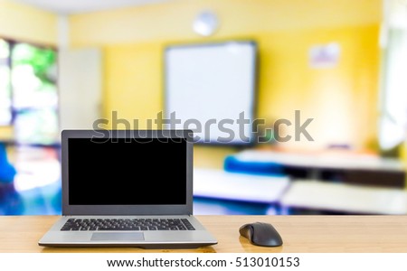 Computer on the table ,blur image of classrooms are empty as background.