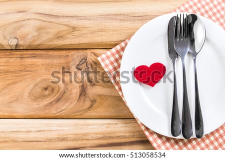 red heart shape with White empty plate with fork and spoon on wooden table for love dinner concept