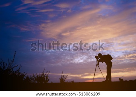 Silhouette of a young photographer with sunset background, taking pictures of the beautiful moments during the sunset.