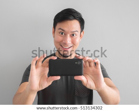 Funny Asian man taking photo with smartphone. Black t-shirt mourn for Thai king.