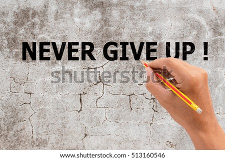 Hand with marker writing the text - Never give up! on grunge background 
