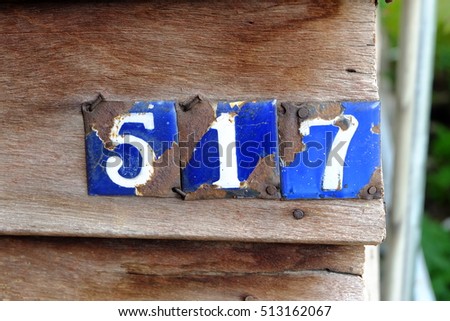 Weathered grunge square metal plate of house number with number 517.