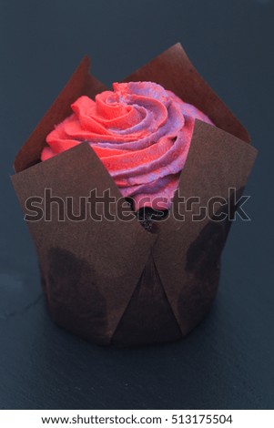 Cupcakes with pink and violet cream on a black stone surface