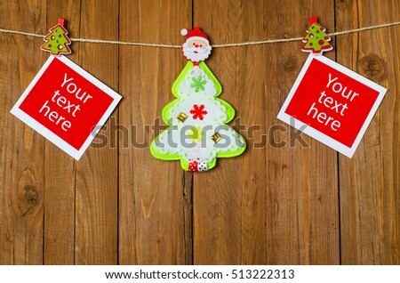 New Year's decorations hang from a rope on a wooden background. Blank photo frames and Christmas tree on the clothespins.