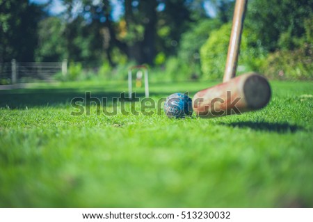 A croquet mallet is hitting a ball on a lawn Royalty-Free Stock Photo #513230032
