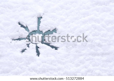 Snow background. Texture of wet snow with sun symbol pattern in the winter window of the car outdoors close-up. Happy joyful sunny image.