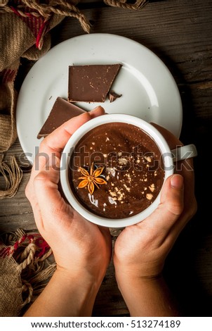 Girl drinks hot chocolate mug, with christmas present on rustic table with blanket or plaid from above, cozy and tasty breakfast or snack. Hands in picture, top view