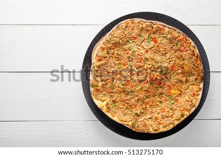 Lahmacun traditional turkish pizza with minced beef or lamb meat, paprika, tomatoes, cumin spice, parsley baked spicy middle eastern arabian food on white wooden table background