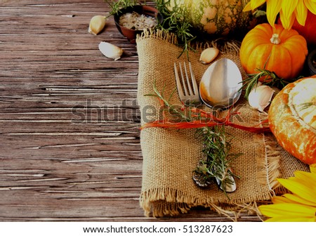 Seasonal wooden table setting with small pumpkins, with cutlery, a napkin on a wooden background, selective focus