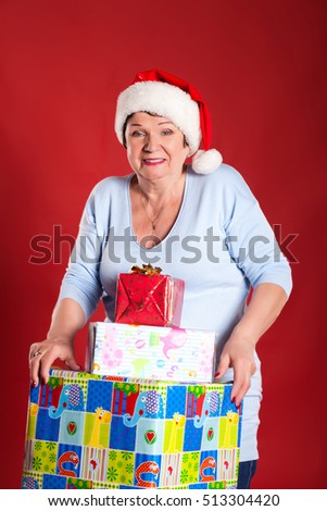 grandmother with gifts for the new year, in the studio on a red background. Concept holidays and shopping