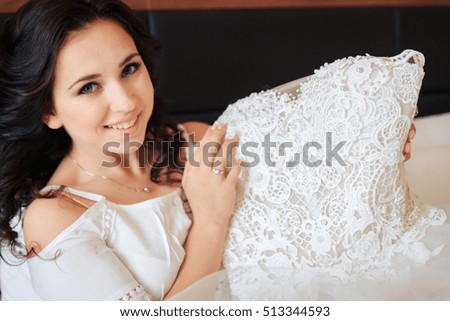 the bride sits on the bed and keeps the wedding dress in the hands