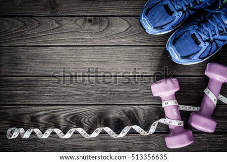 Fitness, healthy and active lifestyles Concept, dumbbells, tape measure, sport shoes on wood background. copy space for text. Top view