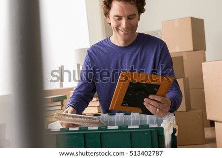 Mature man unpacking picture frame from crate