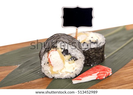 Sushi rolls on wooden Board with leaves of leeks and black sign for logo and name