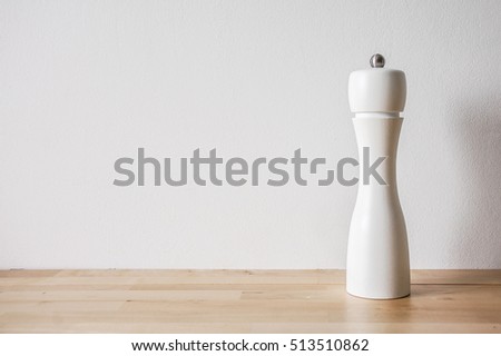 Modern salt grinder made of wood, painted white, standing on wood texture table, front view Royalty-Free Stock Photo #513510862