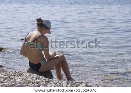 Girl enthusiastically reading book on the beach.
