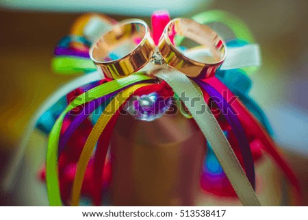 Blurred picture of wedding rings lying over the colorful ribbons