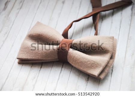 Men's brown, beige bow tie on a wooden background. Accessory for formal dress. Symbol of elegance and fashion for men. Men's casual. Men's and women's accessories. Men's and women's bow tie. Royalty-Free Stock Photo #513542920