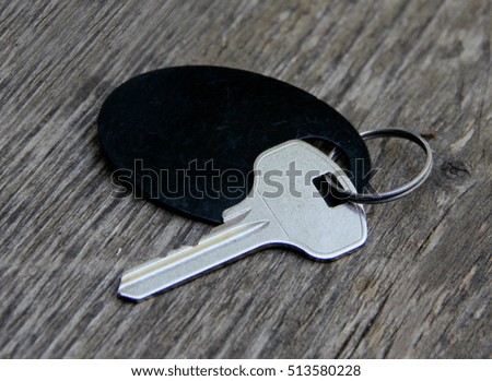 A silver key with black plastic tag on a vintage wooden background