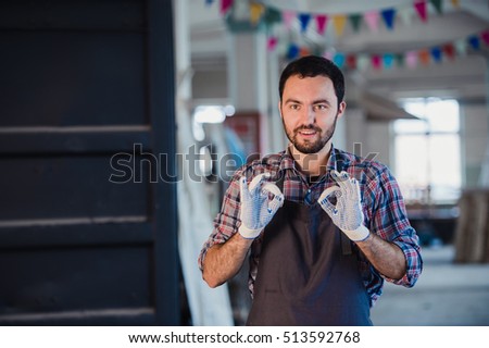Smiling worker gesturing double OK sign at workshop