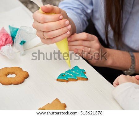 Christmas Treats. Handmade cookies, confection standing on the table. Female hands decorating gingerbread with icing sugar using a pipping bag. Baking holiday cookies. Christmas and New Year. Royalty-Free Stock Photo #513621376