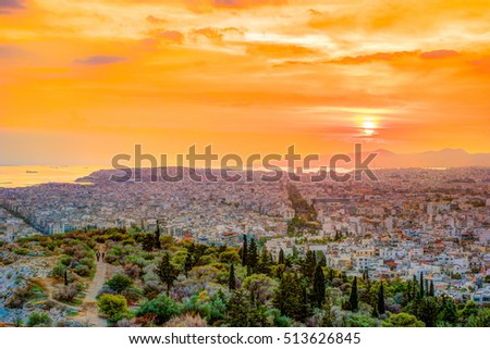 Panorama of Athens at sunset. Beautiful cityscape with seashore and distant islands visible under the red sunset sky. Travel photography.
