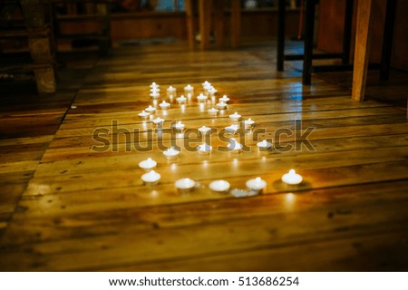 The candles are arranged in rows words "i love you" on wooden floor