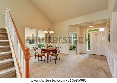 Beige dining room interior with high ceiling and staircase. Elegant table setting and wrought iron chairs. Northwest, USA