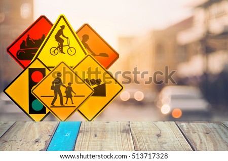 Set of traffic warning sign on blur traffic road with colorful bokeh light and old empty wood table background.Copy space of transportation and travel concept. Product display presentation.Retro tone