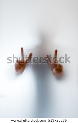 Blurry figure of a man making peace sign behind frosted glass