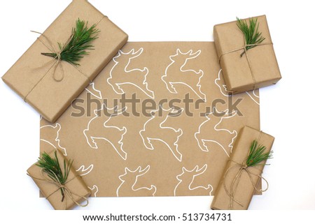Eco style gift wrapping. Kraft paper with a picture of a deer painted white liner. Boxes decorated with pine branches. Copy space, flat lay, top view