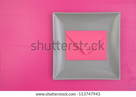 Gray ceramic dish with pink envelope on the wooden table, square  dish