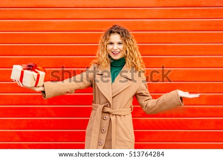 Balance concept. 
Business woman compares the options in hands.
Pretty woman holding her hands out as if balancing or weighing gift and something over red background.