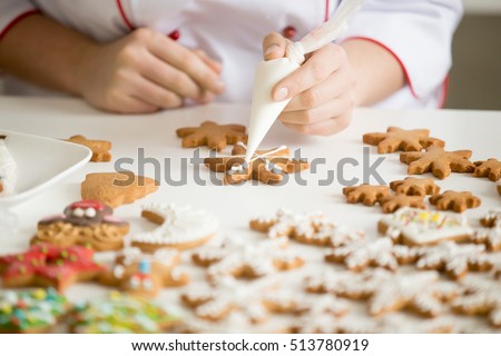 Close up of female confectioner hands decorating gingerbread stars with icing sugar using selfmade pastry bag making cutest Christmas cookies