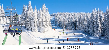 Panorama of ski resort, slope, people on the ski lift, skiers on the piste among white snow pine trees Royalty-Free Stock Photo #513788995
