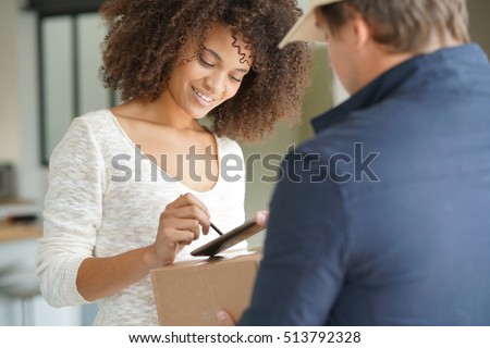 Mixed race woman receiving package from delivery man Royalty-Free Stock Photo #513792328