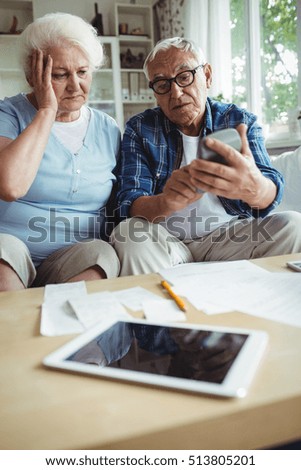 Worried senior couple interacting while checking the bills at home