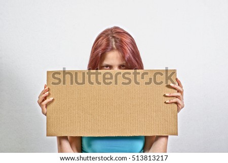 Young Adult Woman in Blue Top Holding a Big Cardboard Inscription, Hiding Her Face Behind It