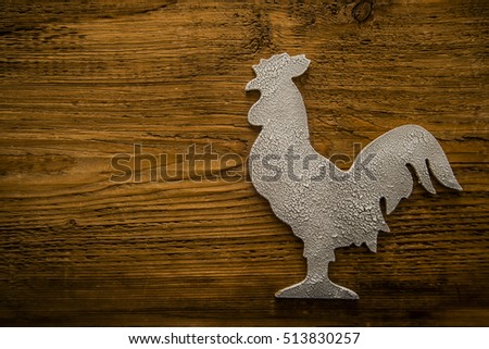 Wooden white snowy rooster. New Year. Cock under white snow flakes lie on wooden board background. empty copy space for inscription or other objects. Idea of happy new  year on the eastern calendar