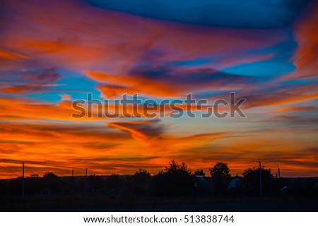 Rural landscape in evening at sunset with bright dramatic red cloudy sky