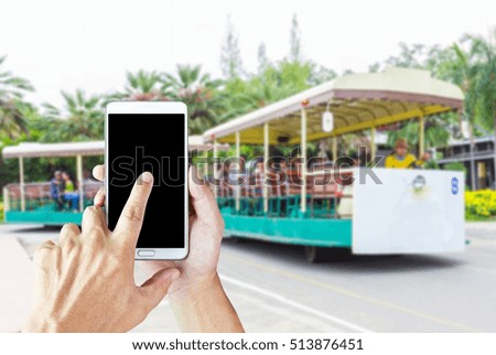 Man use mobile phone , blur image of rickshaw tour as background. 