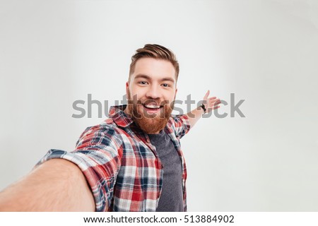 Close up portrait of a cheerful bearded man taking selfie over white background Royalty-Free Stock Photo #513884902