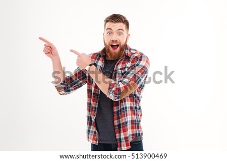 Excited cheerful bearded man pointing fingers away isolated on a white background