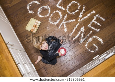 A boy sitting on the floor an playing with flour A picture with a big inscription made from flour saying Love Cooking.